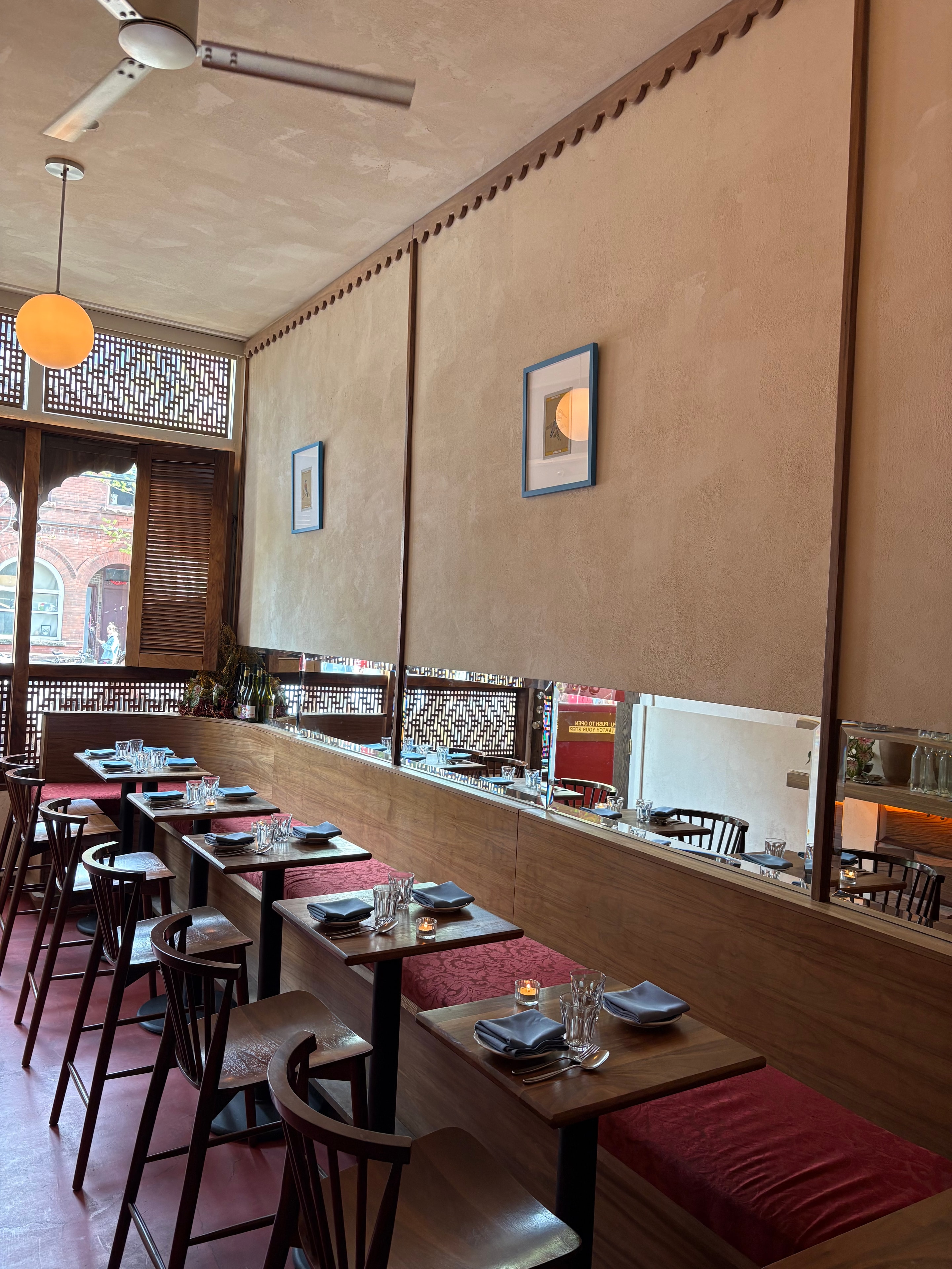 The main dining room at Jamil's Chaat House — walnut banquettes, scarlet velvet, warm sand-coloured walls